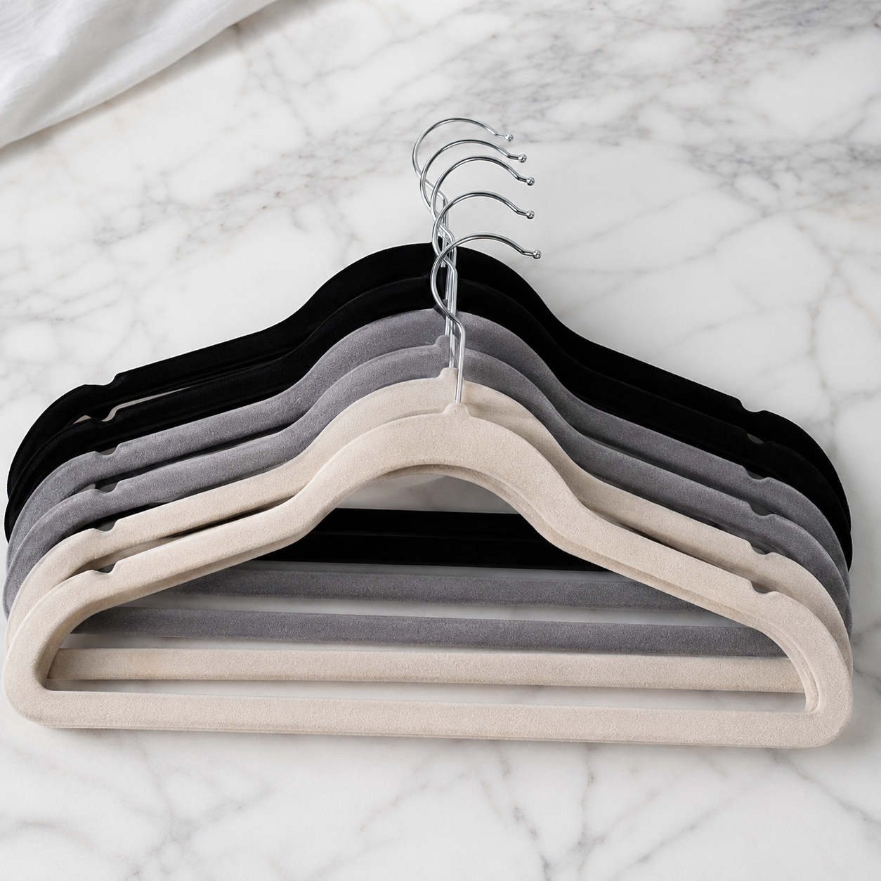 Minimalist white wardrobe featuring premium slim velvet hangers holding beige, cream, gray, and black clothing 